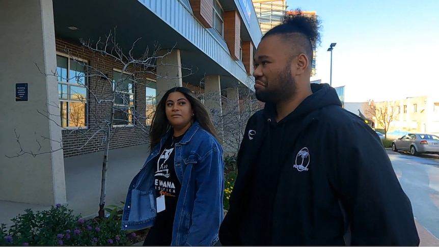 Two people in front of building.