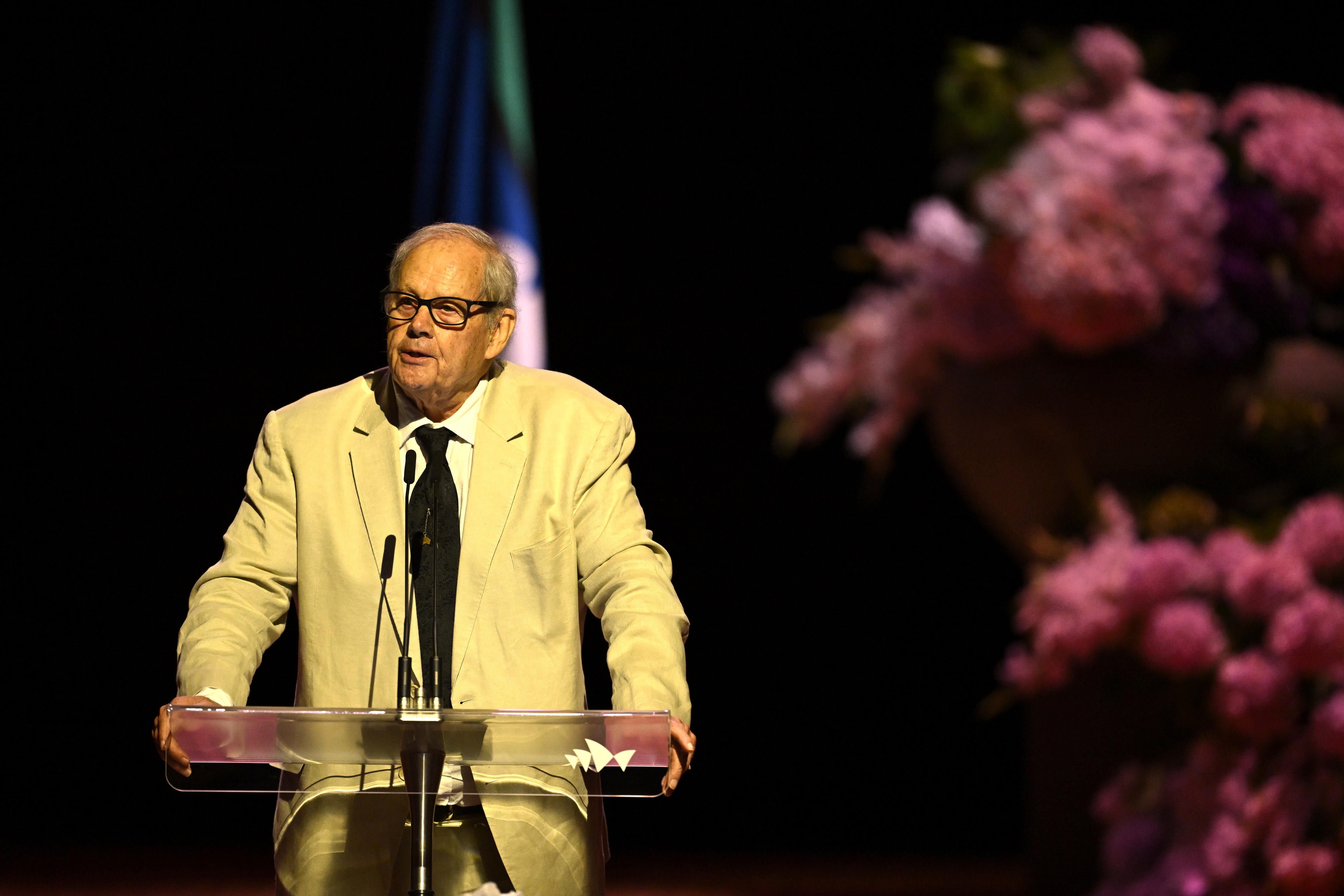 A man in a suit speaks on stage. 