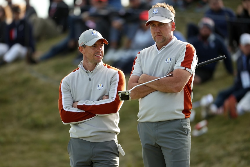 Ian Poulter and Rory McIlroy stand with their arms folded looking disappointed