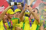 Australian players lift a trophy and spray champagne on a podium in celebration