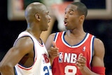 Michael Jordan in a white basketball jersey talks to Kobe Bryant in a red jersey