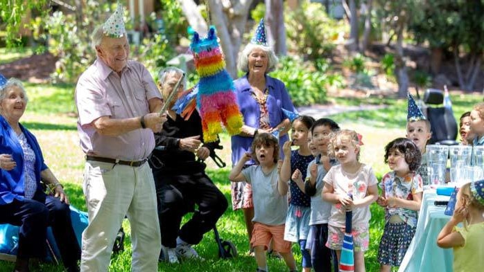 Elderly men and women celebrating a birthday with children.