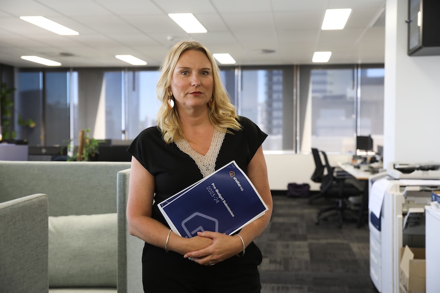 Kath Snell holding a blue Shelter WA report.