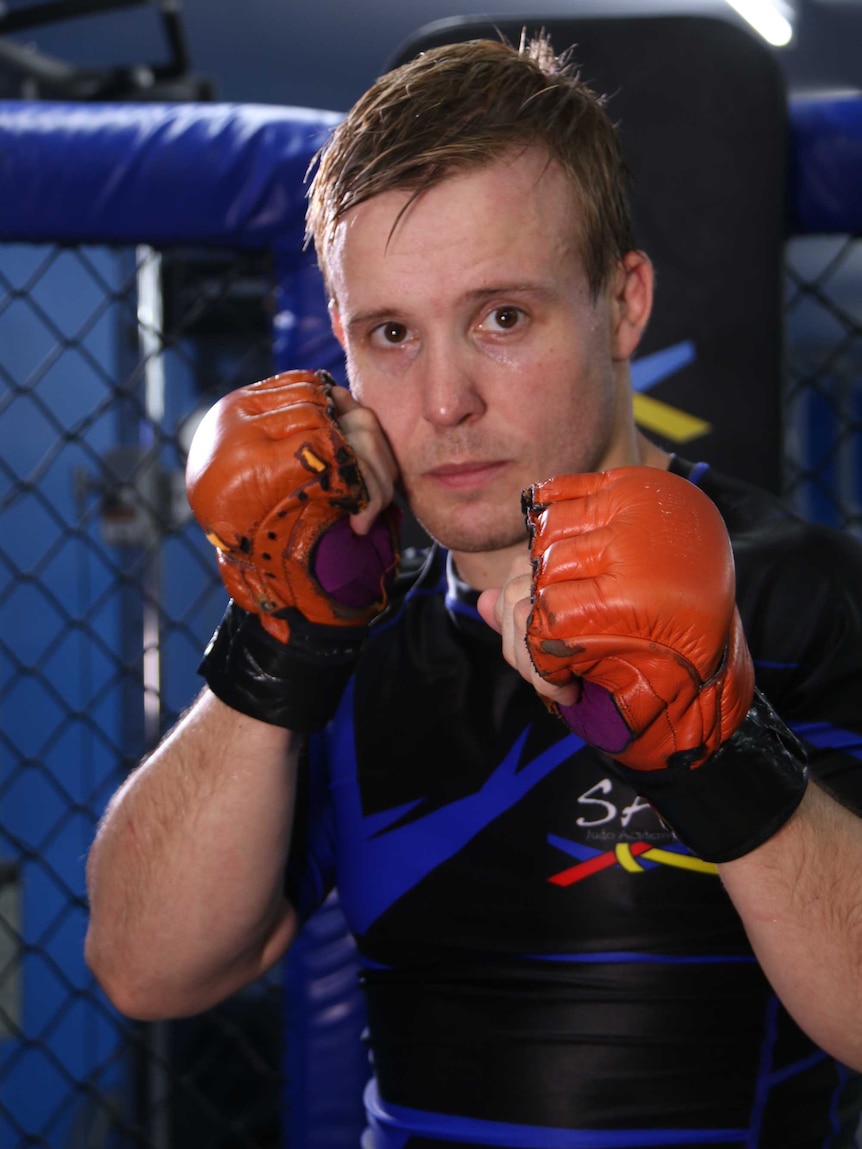 An MMA fighter stares at the camera with his fists up