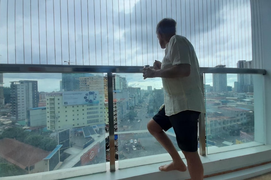 Garry Mulroy looking out from the balcony of a high rise apartment onto the streets of Phnom Penh.