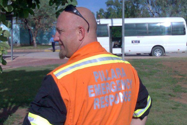 Shaun Southern stands outside with his back turned to the camera and face turned sideways wearing hi-vis clothing near a bus.