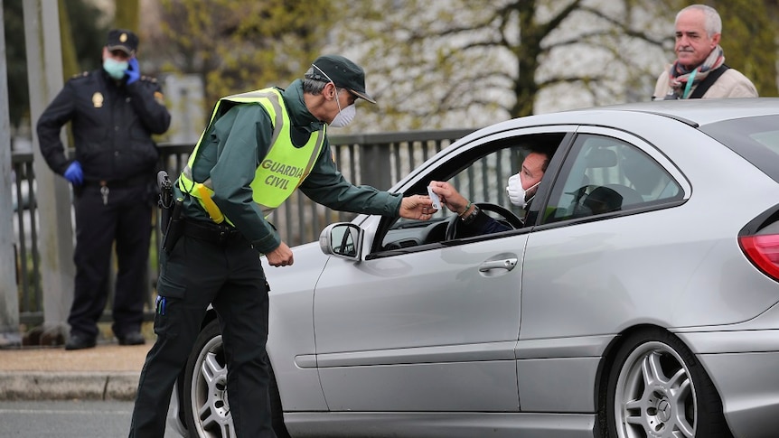 A masked Spanish Guardia Civil officer checks a vehicle entering Spain.