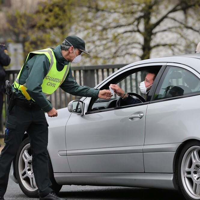 A masked Spanish Guardia Civil officer checks a vehicle entering Spain.