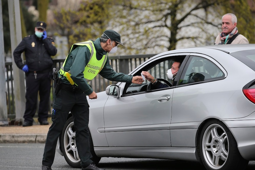 A masked Spanish Guardia Civil officer checks a vehicle entering Spain.