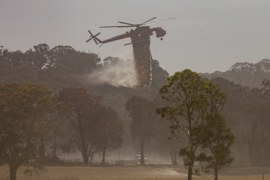 A helicopter dumps water on a fire.