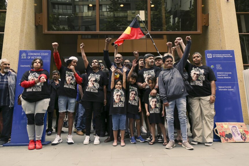Supporters wearing t-shirts with Veronica Nelson and holding Aboriginal flags stand outside court