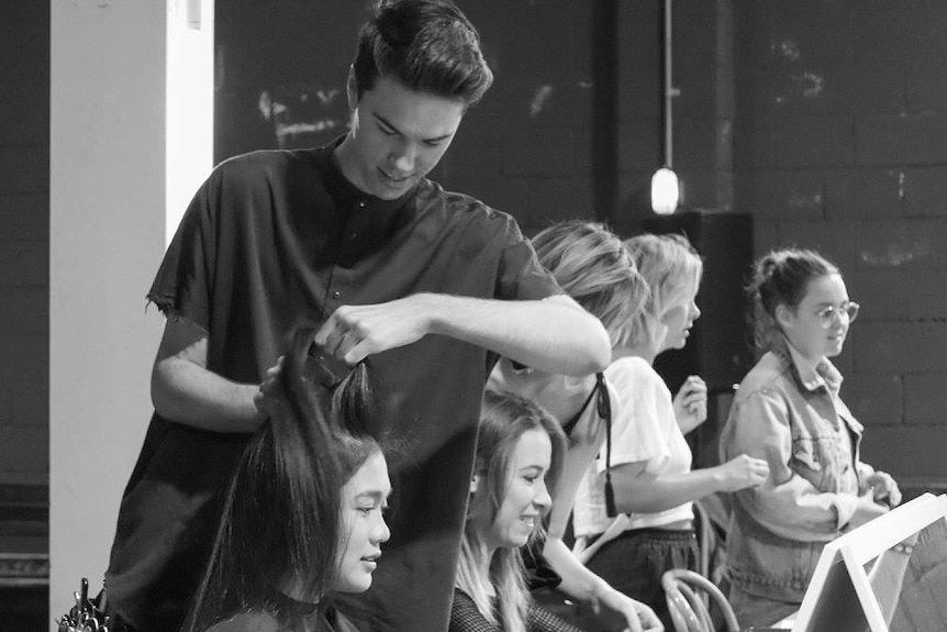 A black and white photo of a hairdresser attending to a client