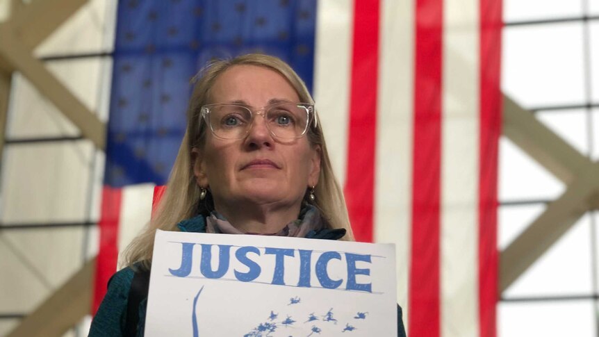 A woman holds a sign reading 'Justice for Justine'.
