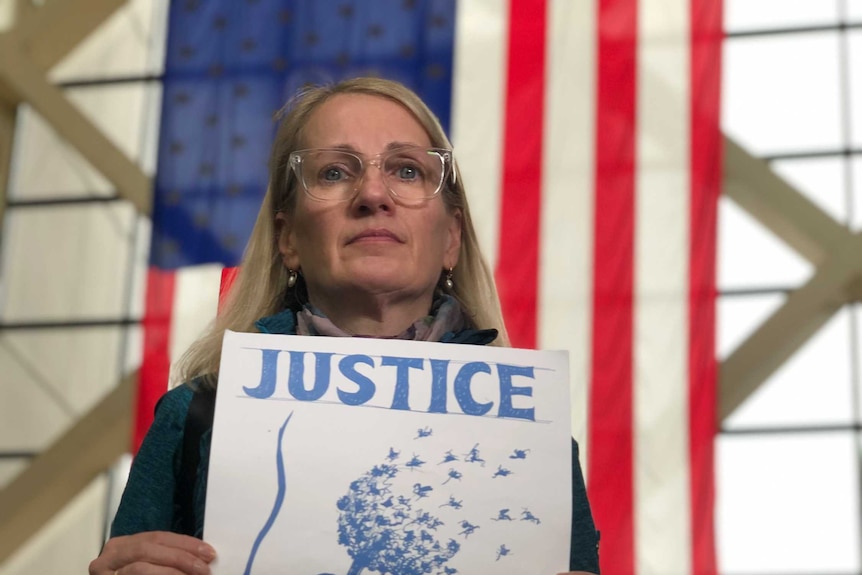 A woman holds a sign reading 'Justice for Justine'.