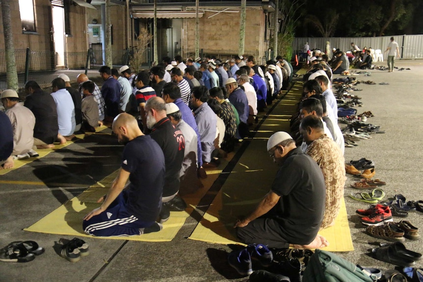 Men kneel on mats to pray at Kuraby mosque.