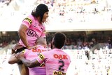 Jarome Luai jumps on Penrith Panthers teammates after a try in an NRL game against the Warriors.