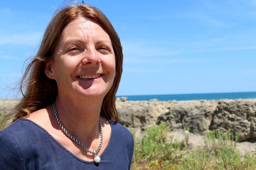 Head shot of a woman with the ocean in the background.