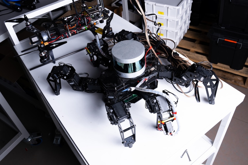 A black robot on a table surrounded by wires