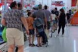 A long queue of shoppers in a supermarket.