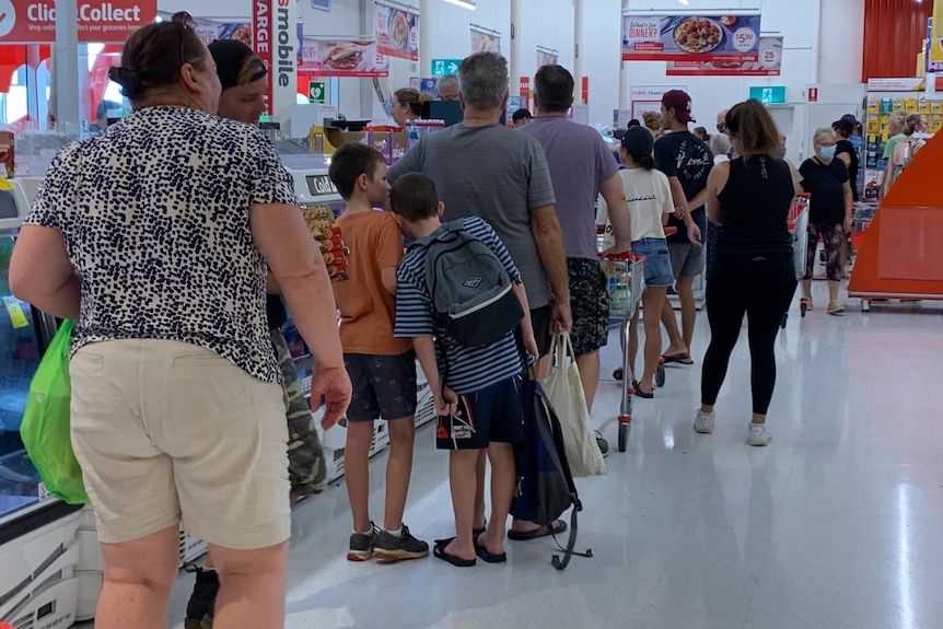 A long queue of shoppers in a supermarket.