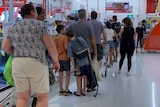 A long queue of shoppers in a supermarket.