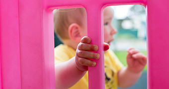 Blurred picture of prison baby through a pink toy with hand in focus.