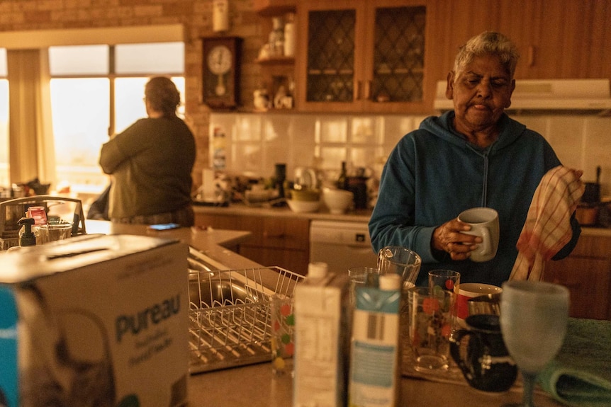 Sandra Patten dries dishes in Alice's kitchen.