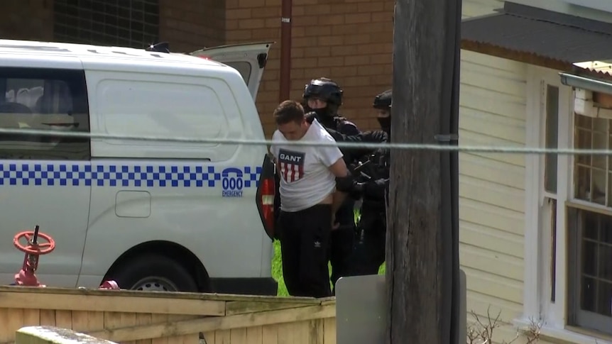 A man being escorted into a van by a police officer.