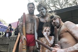 Two Indigenous men, an Indigenous woman and Indigenous four-year-old boy dressed in traditional costume and paint.