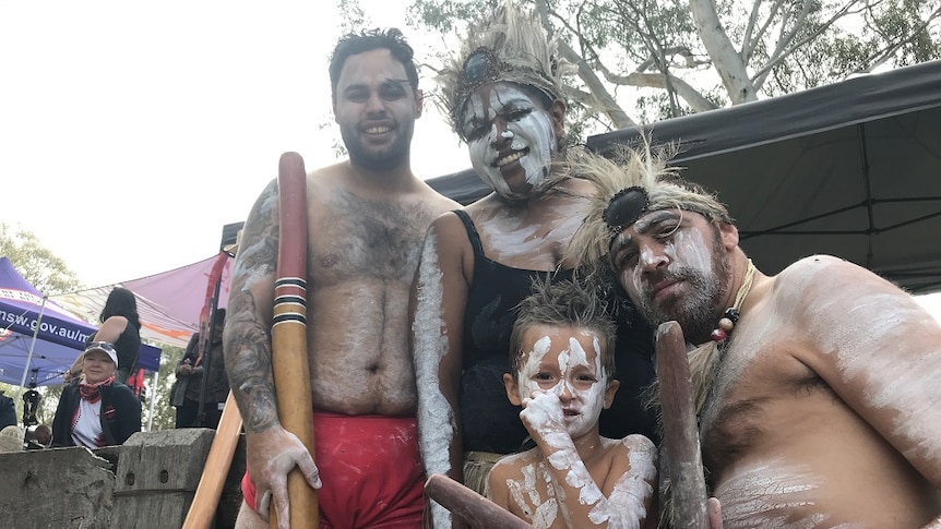 Two Indigenous men, an Indigenous woman and Indigenous four-year-old boy dressed in traditional costume and paint.