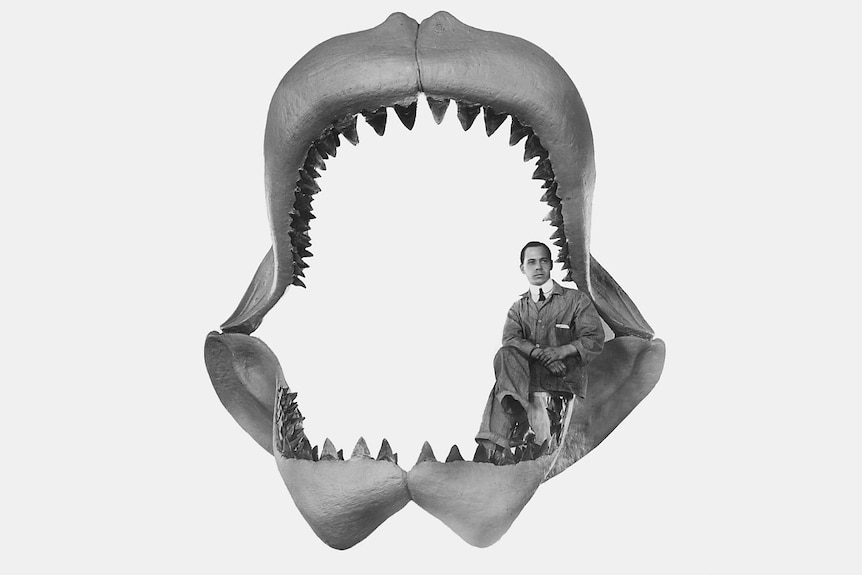 A man sitting inside a huge shark's jaw with teeth