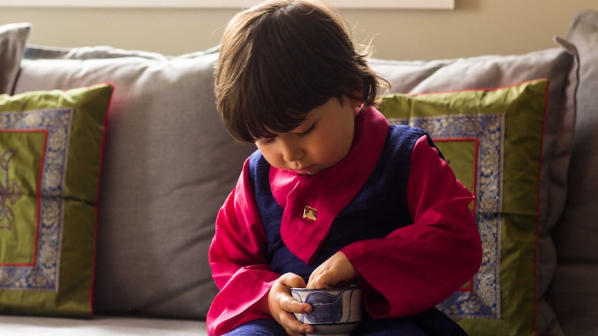 Four-year-old Lhakyi eats sweetened rice by  hand.