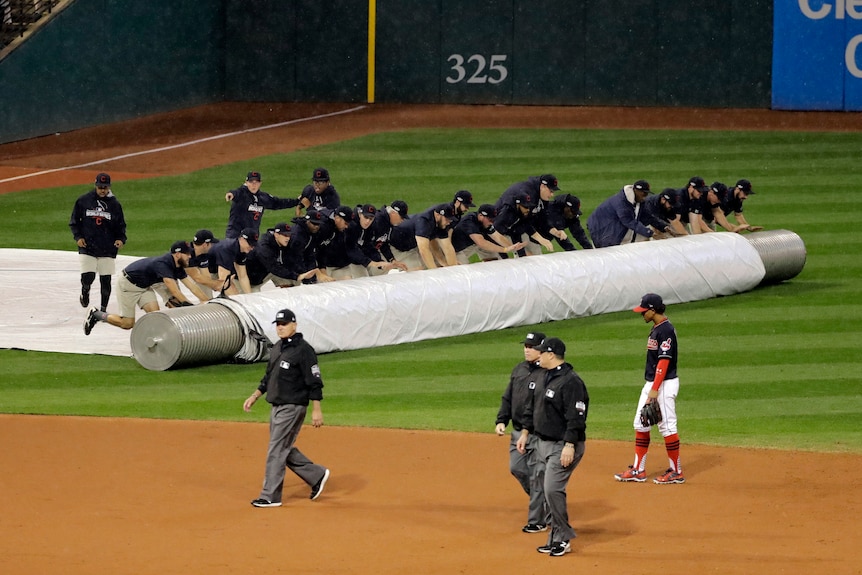 Workers cover the infield during a rain delay in Game Seven of the World Series.