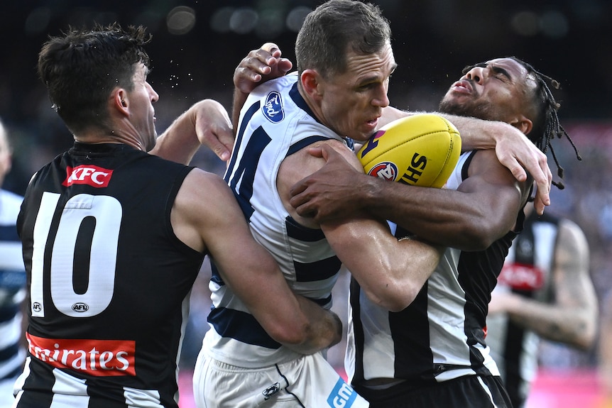 Joel Selwood is tackled by two Collingwood players