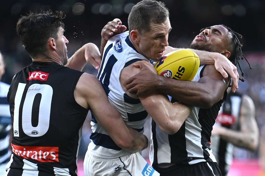 Joel Selwood es abordado por dos jugadores de Collingwood