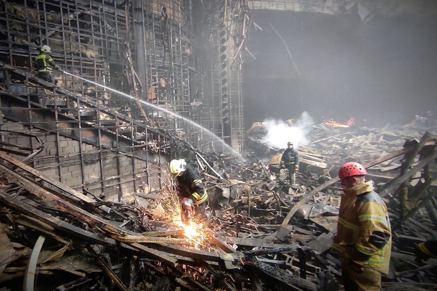 Authorities comb the rubble of the concert hall that was burnt down on Saturday. 