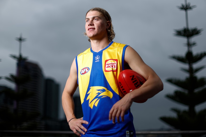 Harley Reid wearing a West Coast jumper holding a football