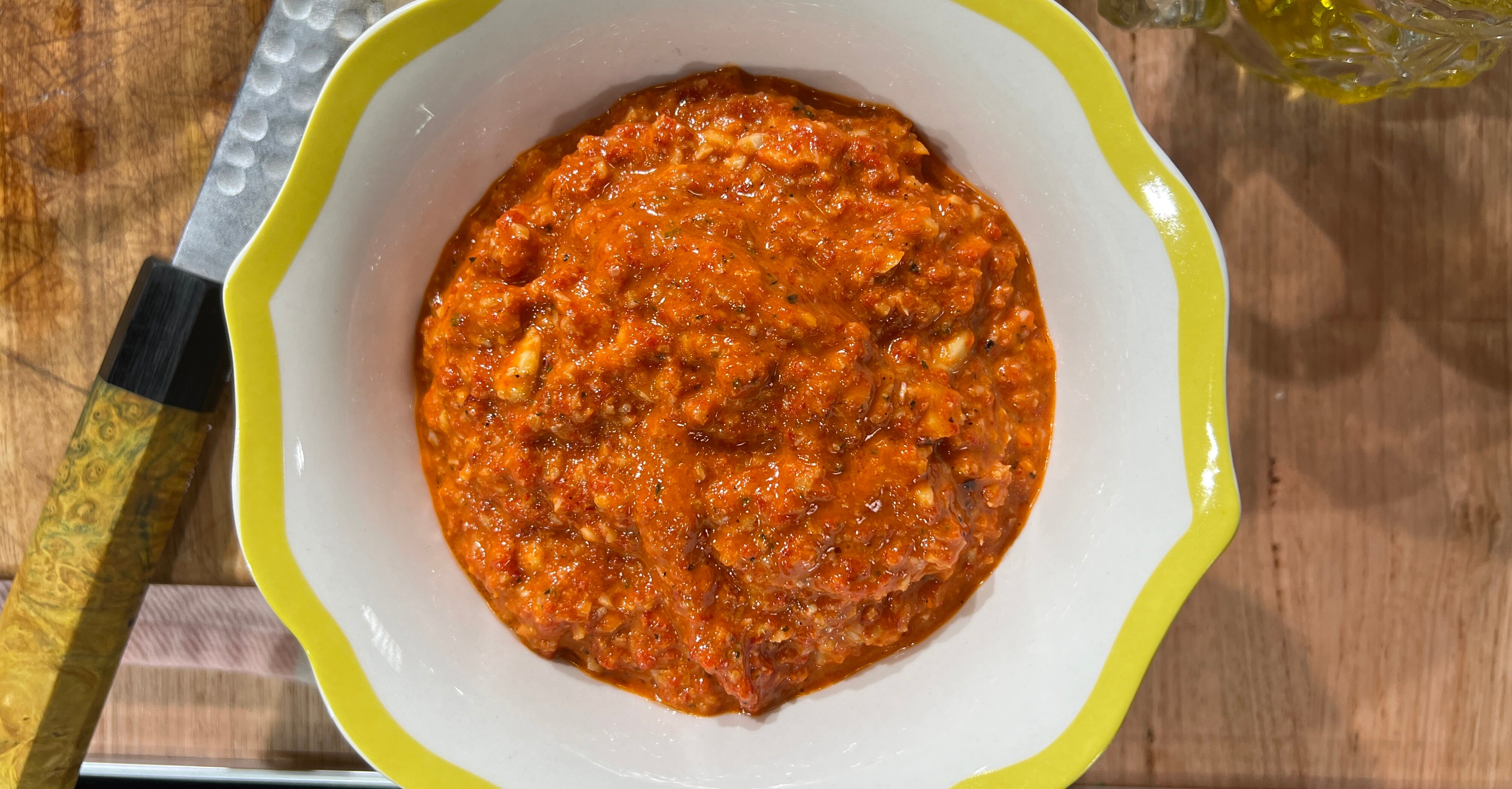 A white bowl with a bright orange sauce in the middle. Shot from above