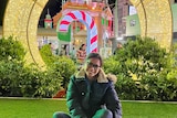 A woman poses in front of elaborate Christmas decorations in Melbourne