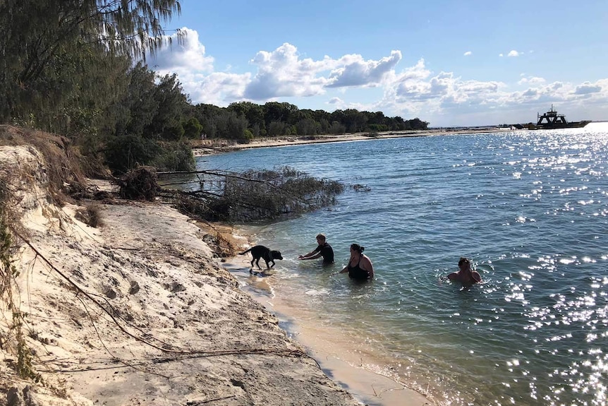 People swimming at Inskip Point where a section of the beach has fallen into the water