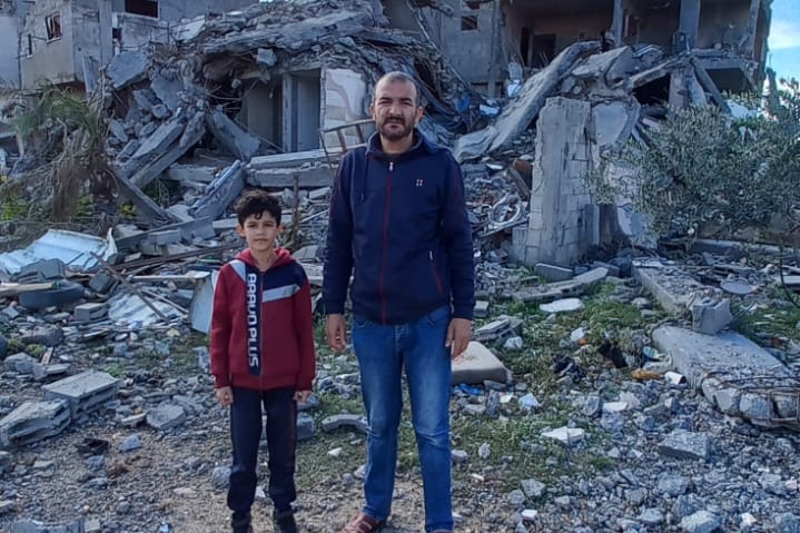 Alaa and his son at the site of their home which has now been reduced to rubble. 