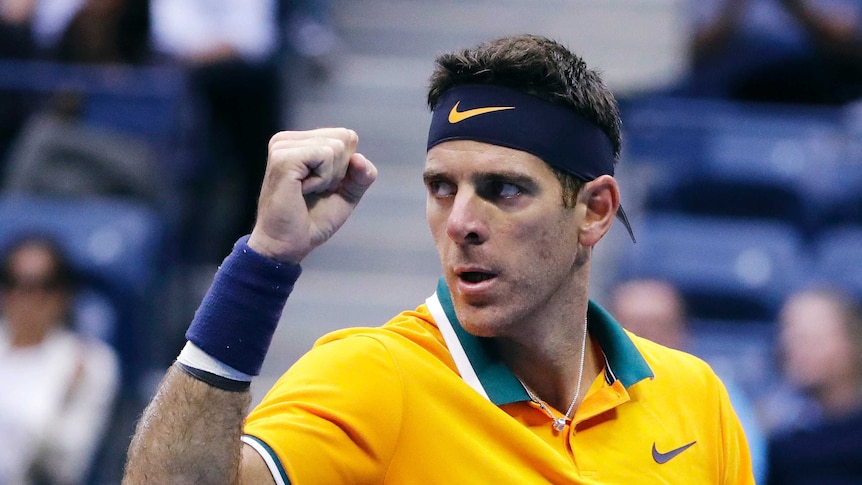 A male tennis player wearing a bight yellow t-shirt clenches his fist and looks to his right