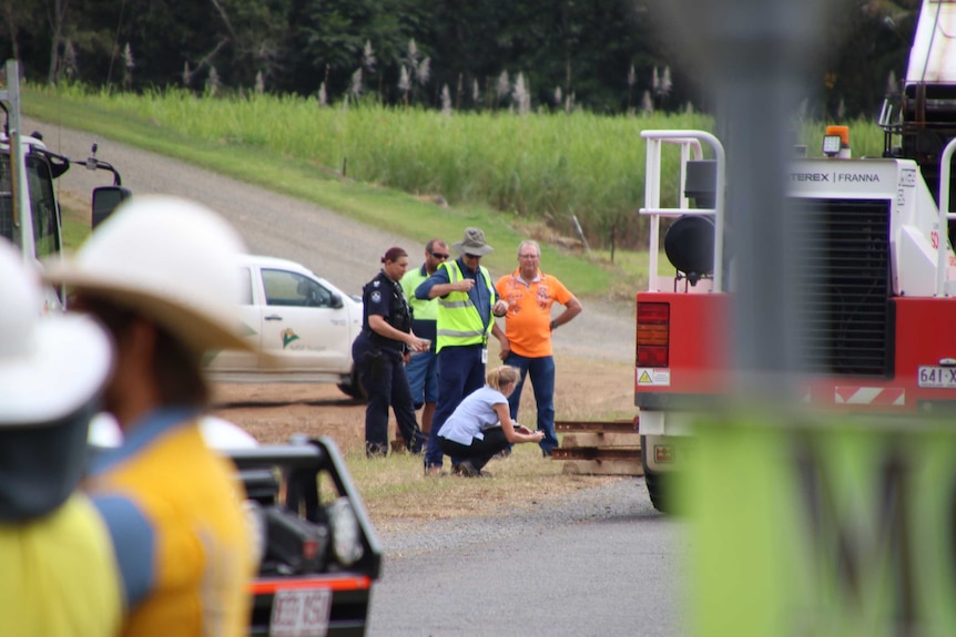 Police and workplace investigators stand together looking at a crane