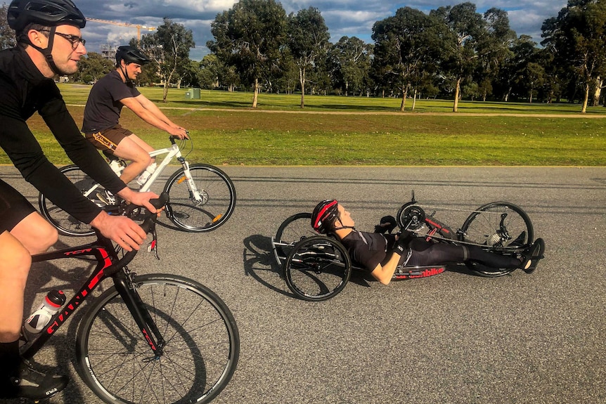 Charles Brice in his handcycling bike with two friends riding bikes behind him