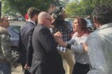 Adrian Attwater surrounded by a throng of people with a woman yelling in his face.