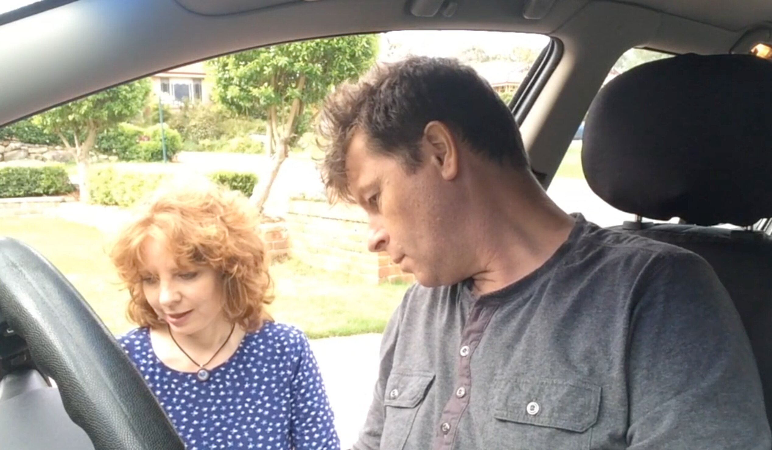 Dr Beth Cheal pictured standing next to a car with a driver at the wheel.