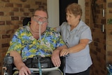 Matt McCracken, sitting in his wheelchair with breathing equipment, with Wendy McCracken standing by his side.