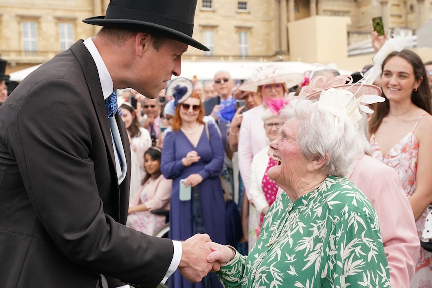 On the left, a man wearing a top hat shakes the hand of an old lady who looks up at him and smiles very bright.