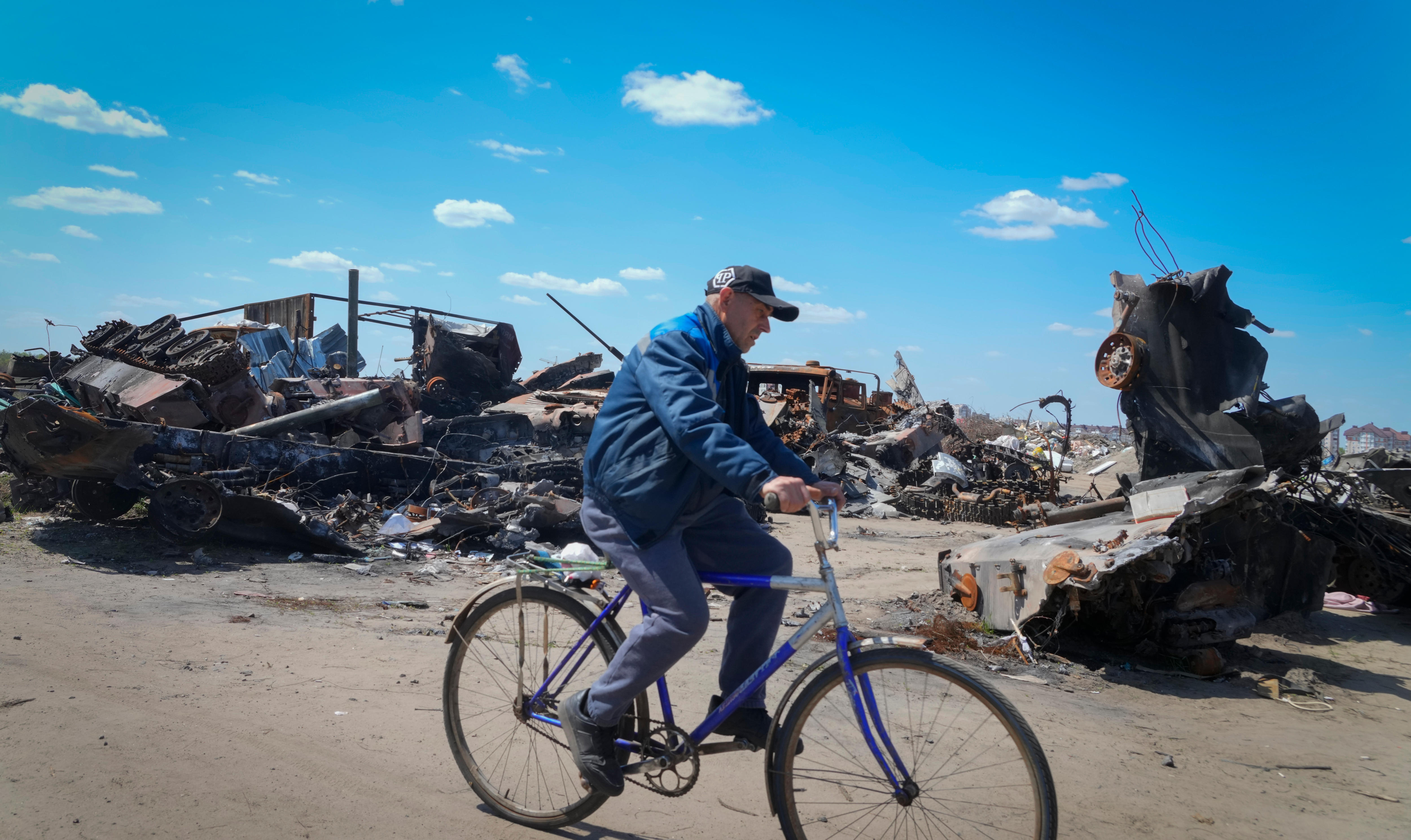 A local resident rides a bike past a destroyed Russian military vehicle