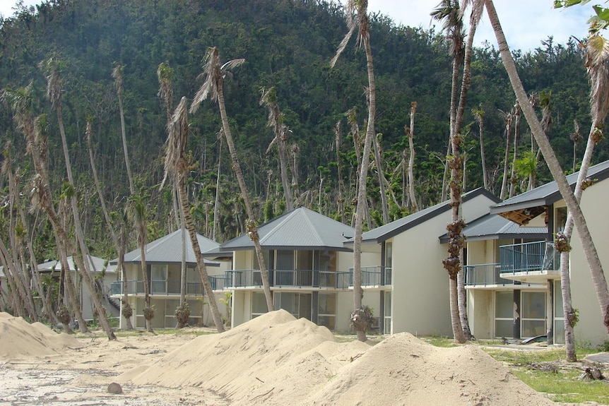 Cyclone-damaged beachfront units and stripped palm trees on Dunk Island.